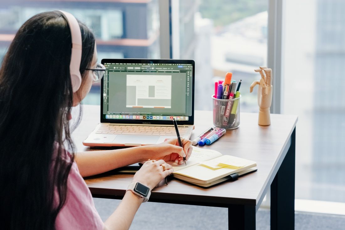 A woman working with a laptop and notebook.